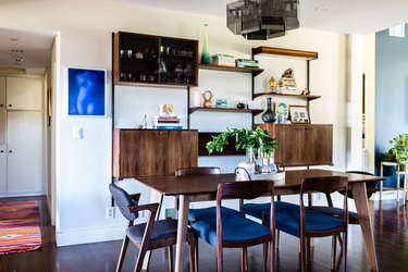 dining room wall decor idea with wood furniture and blue cushioned chairs and a wood sideboard