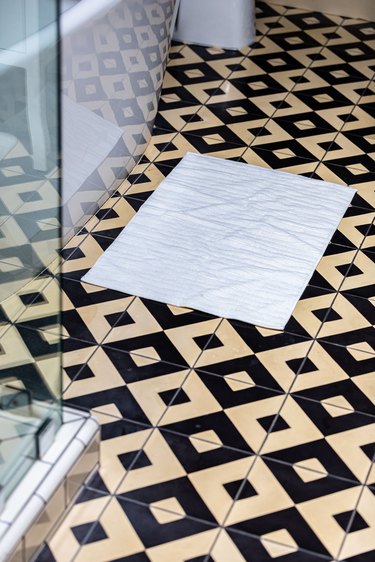 white bathmat on black and yellow tiled bathroom floor