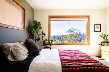 A bedroom with white-green walls and wood framed windows
