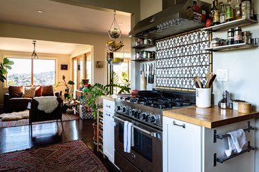 Kitchen with gas range, tile backsplash, wood counters, shelves.