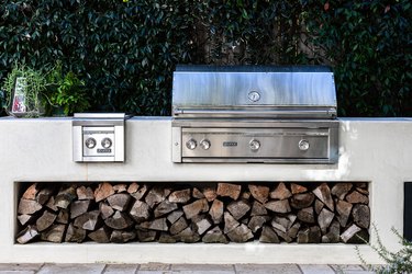 A stainless steel patio grill with firewood