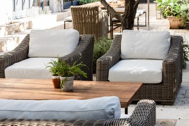 White cushioned patio chairs with a wood coffee table and plants.
