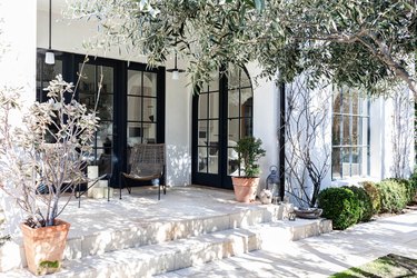 A Mediterranean styled white house with black framed doors and plants