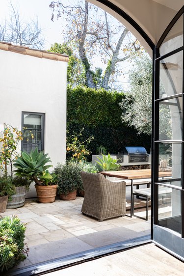 Arched windows looking out to a patio with wicker chairs and plants