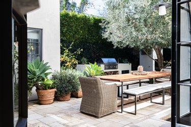 A wicker patio chair and a wood table surrounded by plants