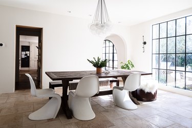 A dining room with large windows, arch doorways and white-brown accents