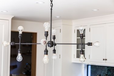 A contemporary industrial light fixture in a white cabinet kitchen