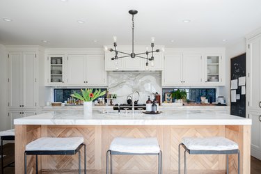Wood kitchen island, white cabinets and a contemporary light fixture