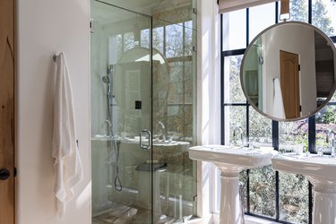 Bathroom with large windows, porcelain sinks, large mirror and glass door shower