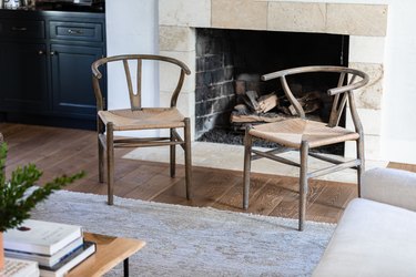 Two living room chairs in front of a fireplace on a wood floor with a neutral rug