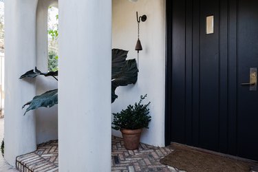 Porch with white columns, a black front door and plants