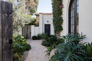 Side of a white home with large curved windows and tropical plants Home Exterior Ideas