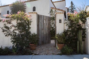 Mediterranean home with a terra-cotta roof and wood door with flower bushes