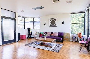 Living room with pink and purple accents, contemporary art, wood floors and large windows
