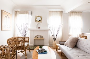 living room with wicker chair, white sofa, and sheer curtains