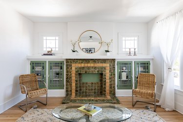 living room with white walls and green cabinets and tile fireplace surround