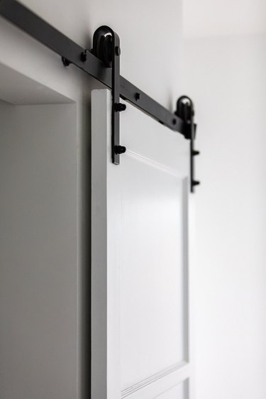 A white sliding door with black hardware hinges