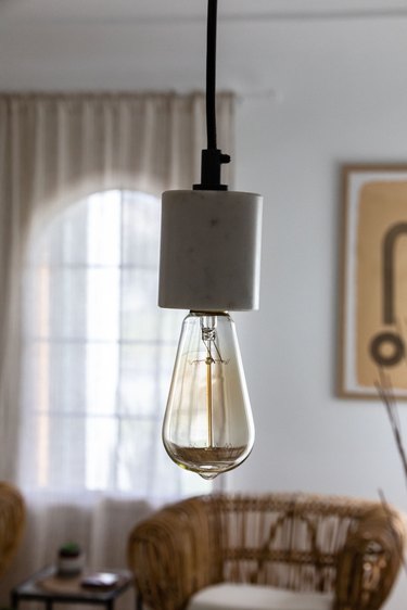 An exposed incandescent light bulb pendant light in a boho living room