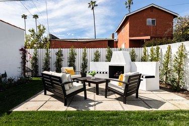 Backyard patio with fireplace, chairs, grass