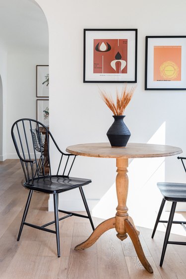 dining table with two chairs and two framed artworks on the wall