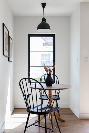 A window with black trim in front of a kitchen table and chairs