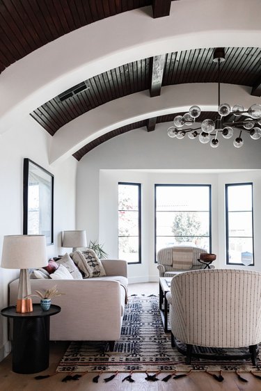 Contemporary living room with wood ceiling arches, multi globe chandelier and beige furniture