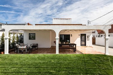 A Mediterranean-style home's back porch and green yard