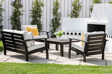 Brown frame patio furniture with white cushions and yellow pillows with a fireplace