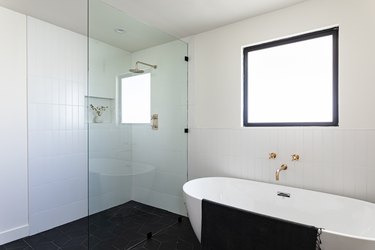 A white bathroom with a freestanding tub and a glass shower door