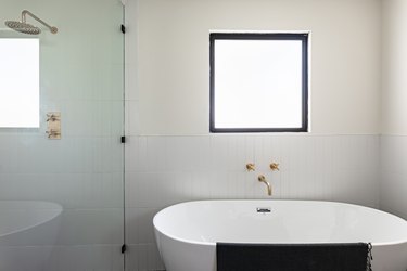 A freestanding bath tub next to a glass shower door