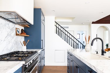 A galley-style kitchen with blue lower cabinets and a gas stove