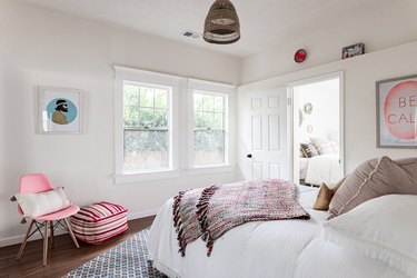 A white-walled bedroom with wood floors and pink accents