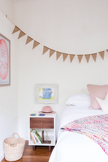 A white-walled bedroom with pink accents and wood floors