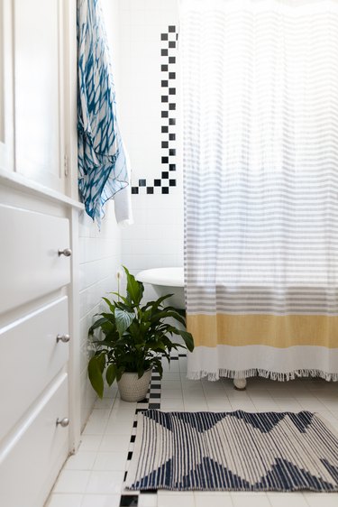 eco-friendly bathroom idea for colorful space with rug and striped shower curtain hanging over claw foot tub