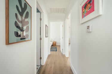 White wall hallway with light wood flooring and framed contemporary wall art
