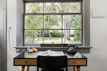 A large aluminum window frame looking out to a forested area