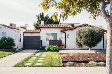 White Spanish style home with red tile and green grass