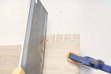 slots being cut into a square of plywood held by a vise