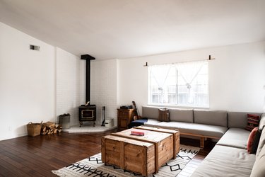 Living room with antique stove, long gray sofa, wood crate coffee table