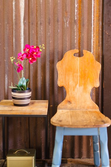 A vintage wood chair with blue legs next to a side table with pink orchids