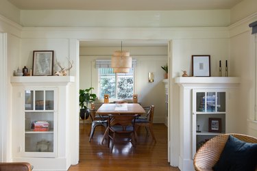 a craftsman-style dining room with built-in cabinets, and a large rattan-shaded pendant light