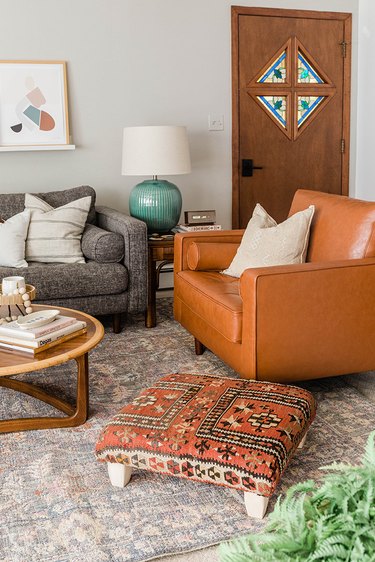 Vintage rug ottoman in a living room with a brown and gray theme, and wood accents