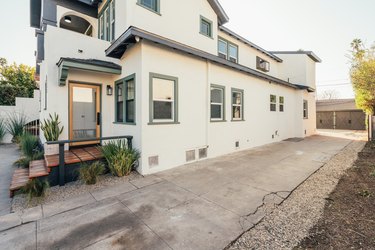 Exterior side of house with view of driveway and back door.