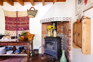 Bohemian kitchen with vintage fireplace in a brick-floral tile alcove, wood furniture, traditional textile, wood beam ceiling