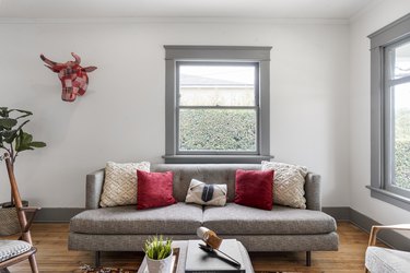 Living room with a gray furniture and window frames, red and white pillows, and contemporary decor