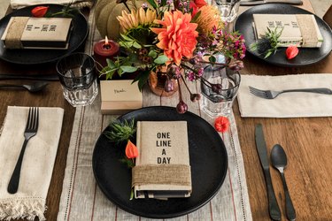 fall party idea with journal party favors on black plates and floral, pumpkin decor