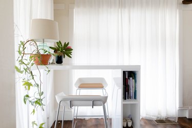 Minimalist dining space with white furniture and curtains and plants