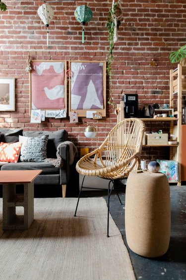 A living room with a brick wall, wood floors and boho furnishings
