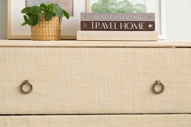 IKEA Tarva dresser with a round pull handle, and covered in burlap, with books on top