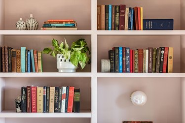 White built-in bookshelves with books, pottery, and a plant.